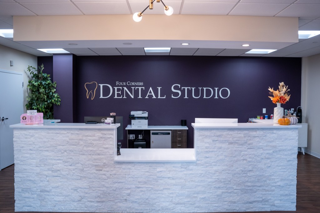 Modern dental office reception area featuring a sleek curved front desk with stone-like finish, dark 