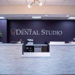 Modern dental office reception area featuring a sleek curved front desk with stone-like finish, dark 