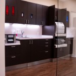 Modern dental office reception area featuring a sleek curved front desk with stone-like finish, dark 