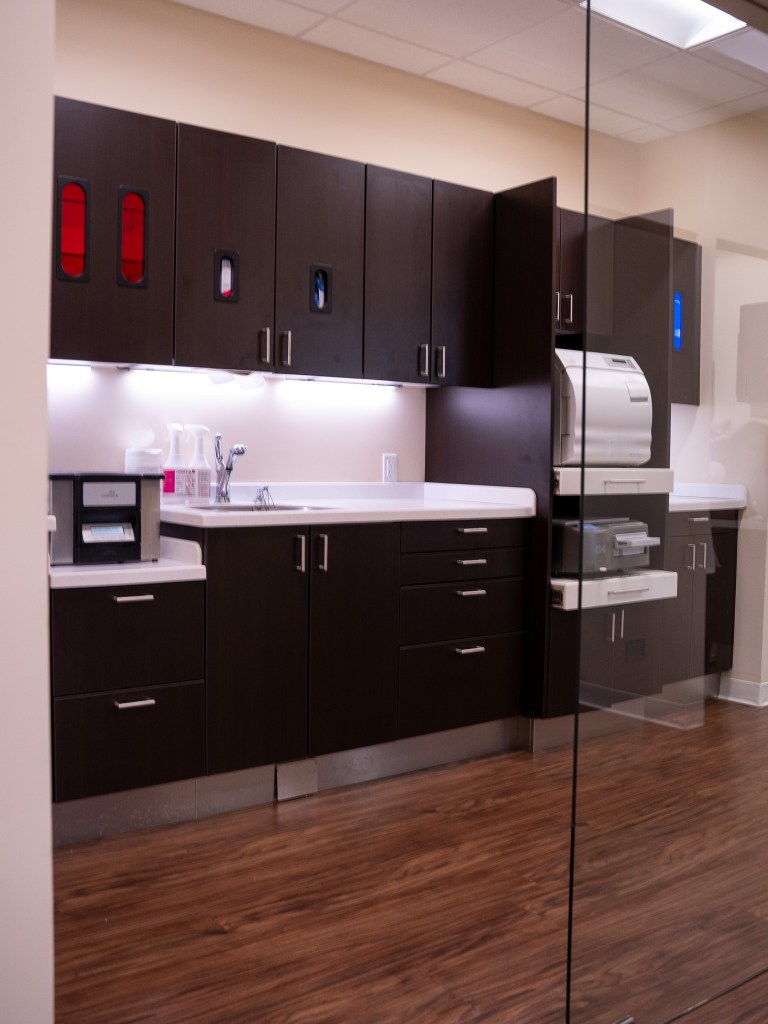 Modern dental office reception area featuring a sleek curved front desk with stone-like finish, dark 
