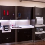 Instrument processing area featuring dark cabinets with red accent lighting, white countertops, sterilization equipment, and organized storage systems.